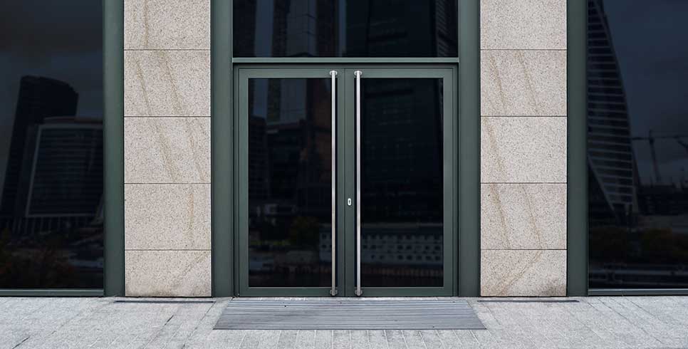 Commercial office building entryway with glass doors and windows covered in decorative Black Out window film